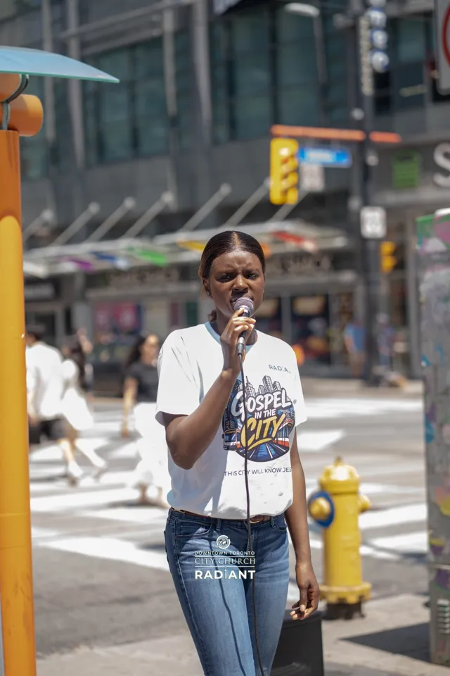 A worshipper in a Gospel in the City t-shirt singing outdoors downtown